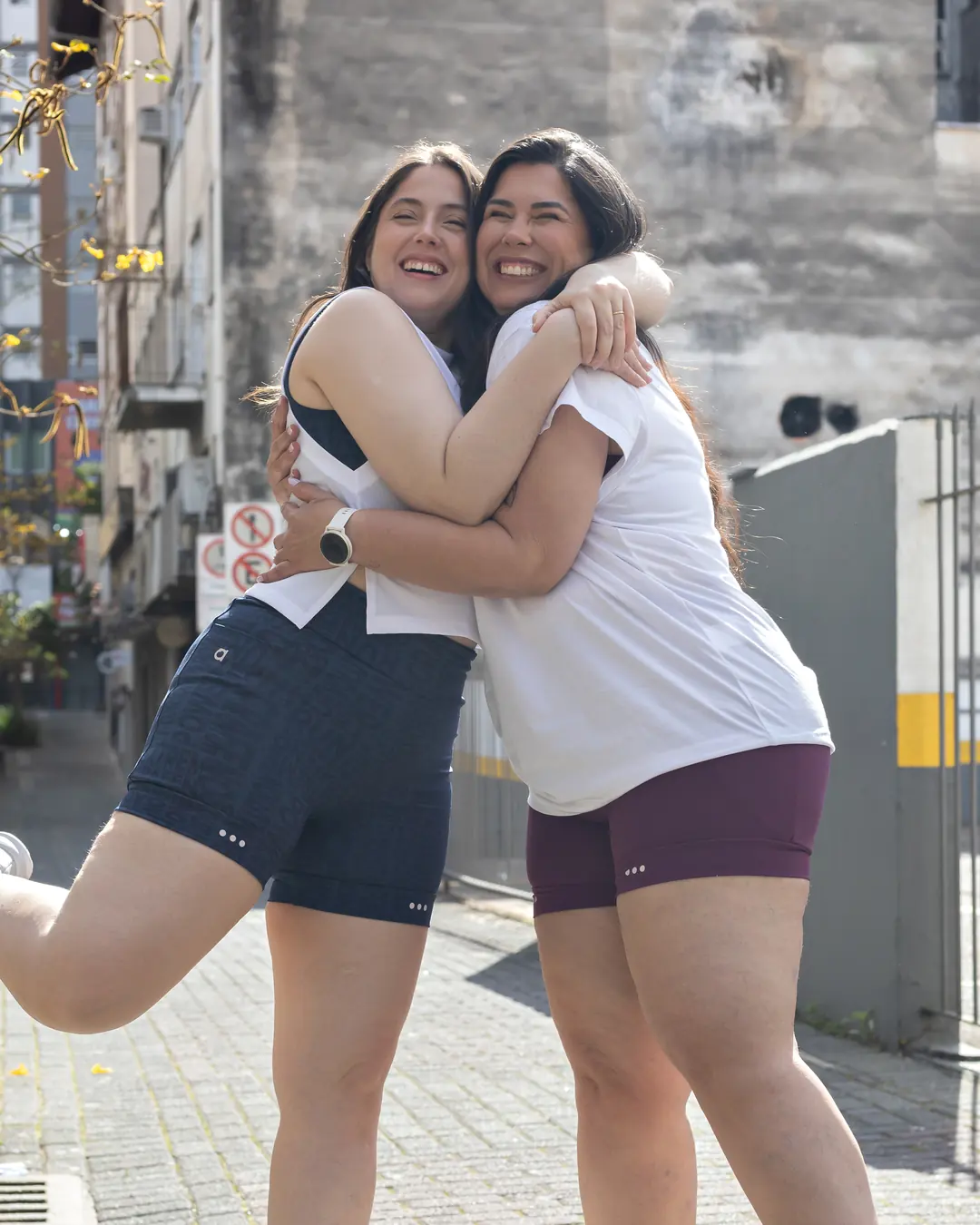 As irmãs Ana Júlia e Priscila, fundadoras da ARA, abraçadas e sorrindo numa rua